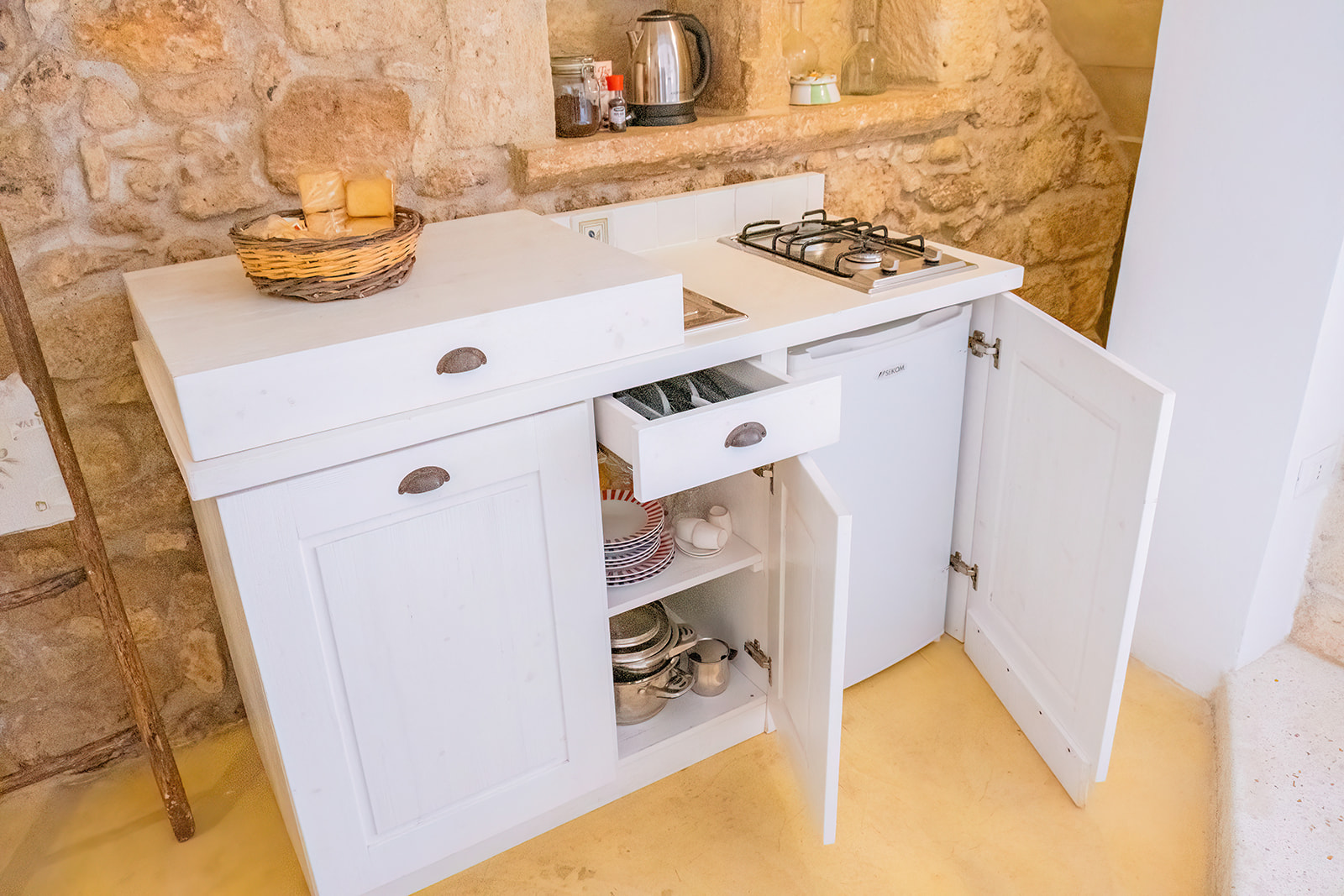 Cucinino della Dimora 2 in legno bianco contro parete in pietra a vista